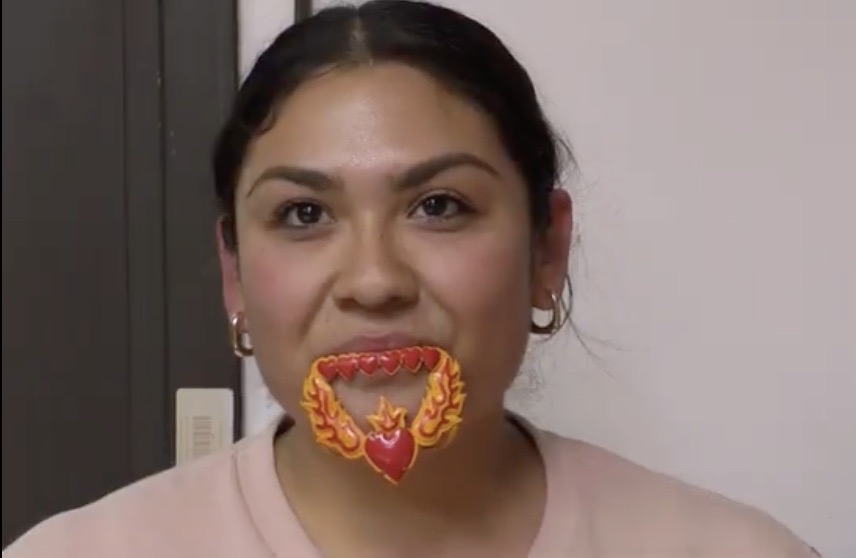 A young woman wearing a piece of metallic art on her mouth